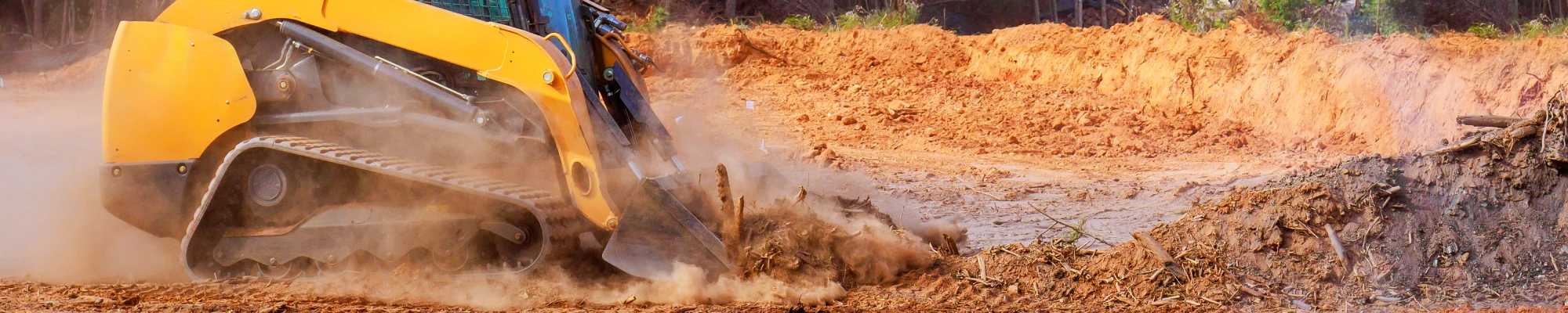Skid steer clearing a wooded North Carolina property before winter